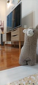a stuffed lamb sitting on the floor in front of a tv at Lovely Nest Piraeus in Piraeus