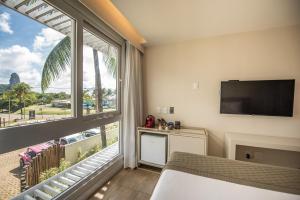 a hotel room with a large window and a television at Pousada Paraíso Noronha in Fernando de Noronha