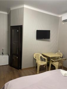 a room with a table and chairs and a tv at Emili in Pizunda