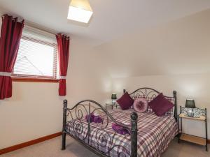 a bedroom with a bed with purple pillows and a window at 25 Langlands Terrace in Kyle of Lochalsh