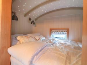 a bedroom with a bed with white sheets at Herbie's Shepherds Hut in Nottingham