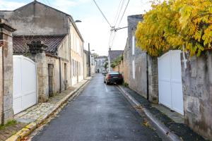 Un callejón con un coche aparcado en una calle con puertas blancas. en L'iris #Netflix #Centre-ville, en Cognac