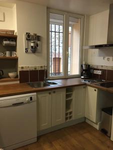 een keuken met witte kasten, een wastafel en een raam bij Studio Portus Veneris, proche criques et Collioure in Port-Vendres