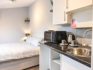 a kitchen with a sink and a microwave and a bed at The Park Inn Piggery in Newton Abbot