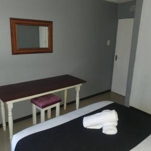 a bedroom with a table and a bench and towels at Imanna 111 in Durban +3 photos