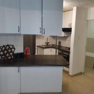 a kitchen with white cabinets and a black counter top at Imanna 111 in Durban