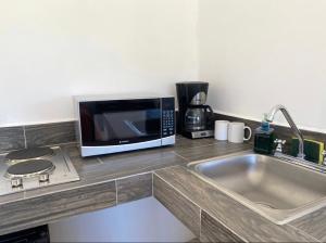 eine Küchentheke mit Mikrowelle und Spüle in der Unterkunft Villa Paraíso in La Ventana