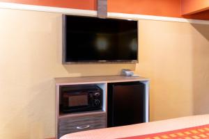 a room with a microwave and a television on a wall at Geneva Motel in Inglewood