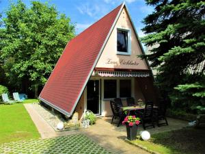 a house with a red roof with a table and chairs at Ferienhaus-Zum-Eichkater-am-Duemmer-See 