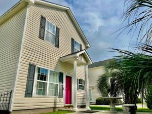 een wit huis met een rode deur en een palmboom bij Lovely Home Near Myrtle Beach in Myrtle Beach