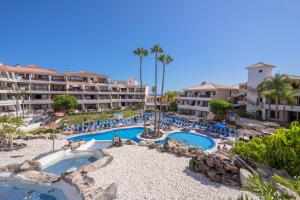a resort with two pools and chairs and palm trees at Apartamentos Golf del Sur Tenerife in San Miguel de Abona