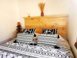 1 dormitorio con 1 cama con almohadas blancas y negras en Kimün Rise Cabaña Céntrica Villarrica en Villarrica