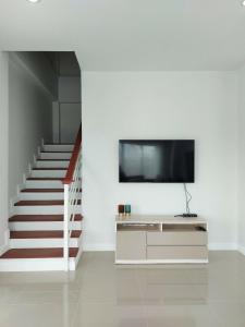 a living room with a tv and a staircase at Pat Holiday Home in Cha Am