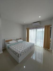 a bedroom with a bed and a large window at Pat Holiday Home in Cha Am