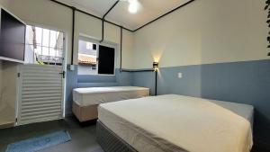 - une chambre avec 2 lits et une fenêtre dans l'établissement Suíte n° 07 - Praia das Pitangueiras, à Guarujá
