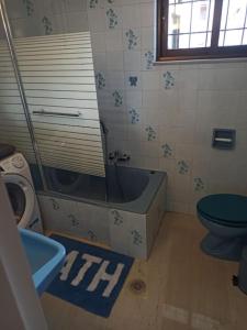 a bathroom with a blue tub and a toilet at Urban Mountain House in Karpenision