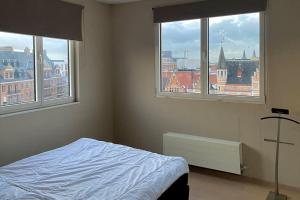 1 dormitorio con 2 ventanas y 1 cama. en Luxe penthouse center Kortrijk, en Cortrique