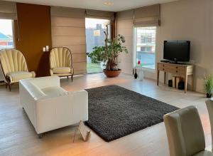 sala de estar con sofá blanco y TV en Luxe penthouse center Kortrijk, en Cortrique