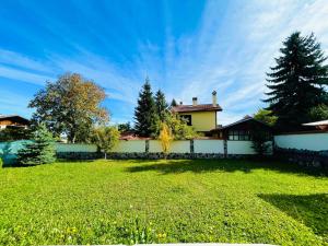 a house with a yard with a fence and trees at Bebalkan guesthouse in Raduil