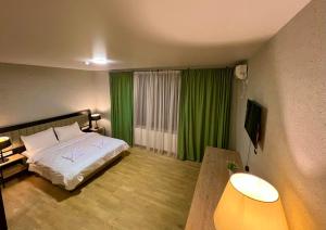 1 dormitorio con 1 cama y cortina verde en Green Hotel ANG, en Telavi