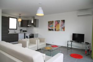 a living room with white furniture and a kitchen at Résidence Isola Hotel in Borgo