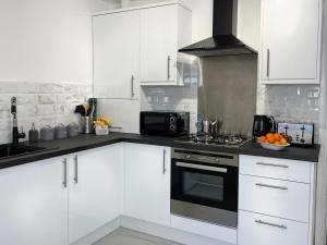 a kitchen with white cabinets and a stove top oven at Harland View Apartment in Belfast
