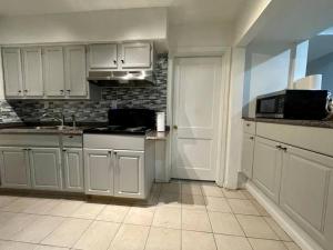 una cocina con armarios blancos y fregadero en Renovated guest house en Hyattsville