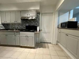 a kitchen with white cabinets and a sink at Renovated guest house in Hyattsville
