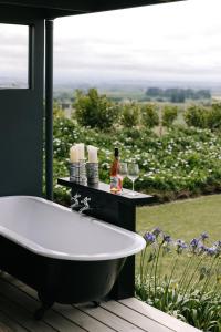 a bath tub sitting on a deck next to a window at Birds Eye View in Havelock North