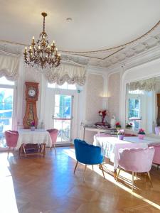 ein Esszimmer mit 2 Tischen und einer Uhr in der Unterkunft Hôtel Le Manoir in Barr