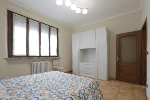 a bedroom with a bed and a cabinet and windows at Langhe Apartament in Monforte dʼAlba