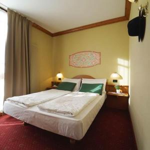 a bedroom with a bed with white sheets and green pillows at Appartamento 50 mq in Palace Ponte di Legno in Ponte di Legno