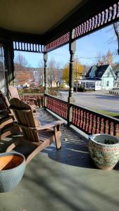 Un porche con dos sillas y dos tazones. en The Elizabeth Inn and Restaurant, en Bethel