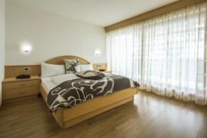 um quarto com uma cama e uma grande janela em Ciasa Vilin em Corvara in Badia