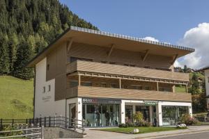 un bâtiment avec un magasin en face d'une montagne dans l'établissement Ciasa Vilin, à Corvara in Badia