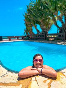 a woman in sunglasses is standing in front of a swimming pool at Mar a Vista in Porto De Galinhas