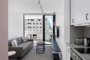 The Flamingo Private Apartments by Perch Stays في كيب تاون: مطبخ وغرفة معيشة مع أريكة وطاولة