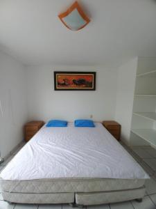 una camera da letto con un letto bianco con cuscini blu di Departamento super cómodo Playa Naplo a Naplo