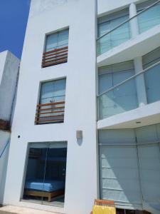 un edificio bianco con finestre di vetro sul lato di Departamento super cómodo Playa Naplo a Naplo