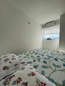 a bedroom with a bed with a floral comforter and a window at Apartamentos Sierra Verde Living in Apartadó