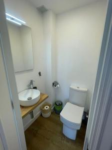 a bathroom with a sink and a toilet and a mirror at Covelodge - Piso a pocos metros de la playa in Pontevedra