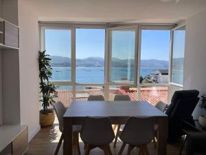 una sala da pranzo con tavolo, sedie e una grande finestra di Covelodge - Piso a pocos metros de la playa a Pontevedra