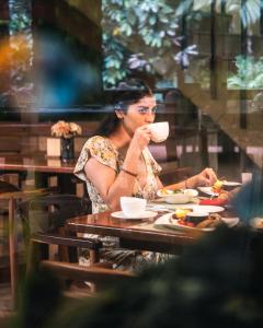 una mujer sentada en una mesa bebiendo una taza de café en Arahuana Jungle Resort & Spa, en Tena