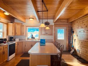 una cocina con armarios de madera y una mesa con sillas. en Balsam Hill Lodge - Sleeps 15, en Island Park