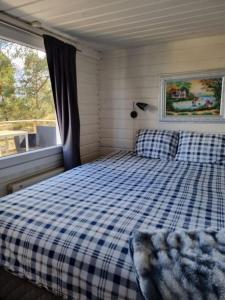Un dormitorio con una cama azul y blanca a cuadros y una ventana en Nils Bastu Spa och Övernattningstuga en Tyresö