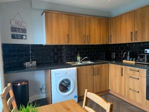 a kitchen with a washing machine and a wooden cabinets at Fantastic Large 2 X Bedroom Flat, Free Parking in Sale