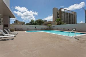 a swimming pool with lounge chairs next to a building at Royal Kuhio 1602 - Spacious Studio with Stunning Mountain Views in the Heart of Waikiki! in Honolulu