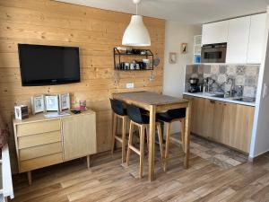 una cucina con parete in legno, tavolo e TV di Studio 4 pers, ménage inclus à Val Thorens a Val Thorens