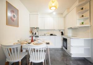 a kitchen with white cabinets and a table and chairs at Bonito apartamento equipado, cerca de la playa in Empuriabrava +6 photos