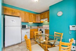 a kitchen with a glass table and a white refrigerator at Royal Kuhio 1702 - Spacious Studio with Stunning Mountain City Views in the Heart of Waikiki! in Honolulu
